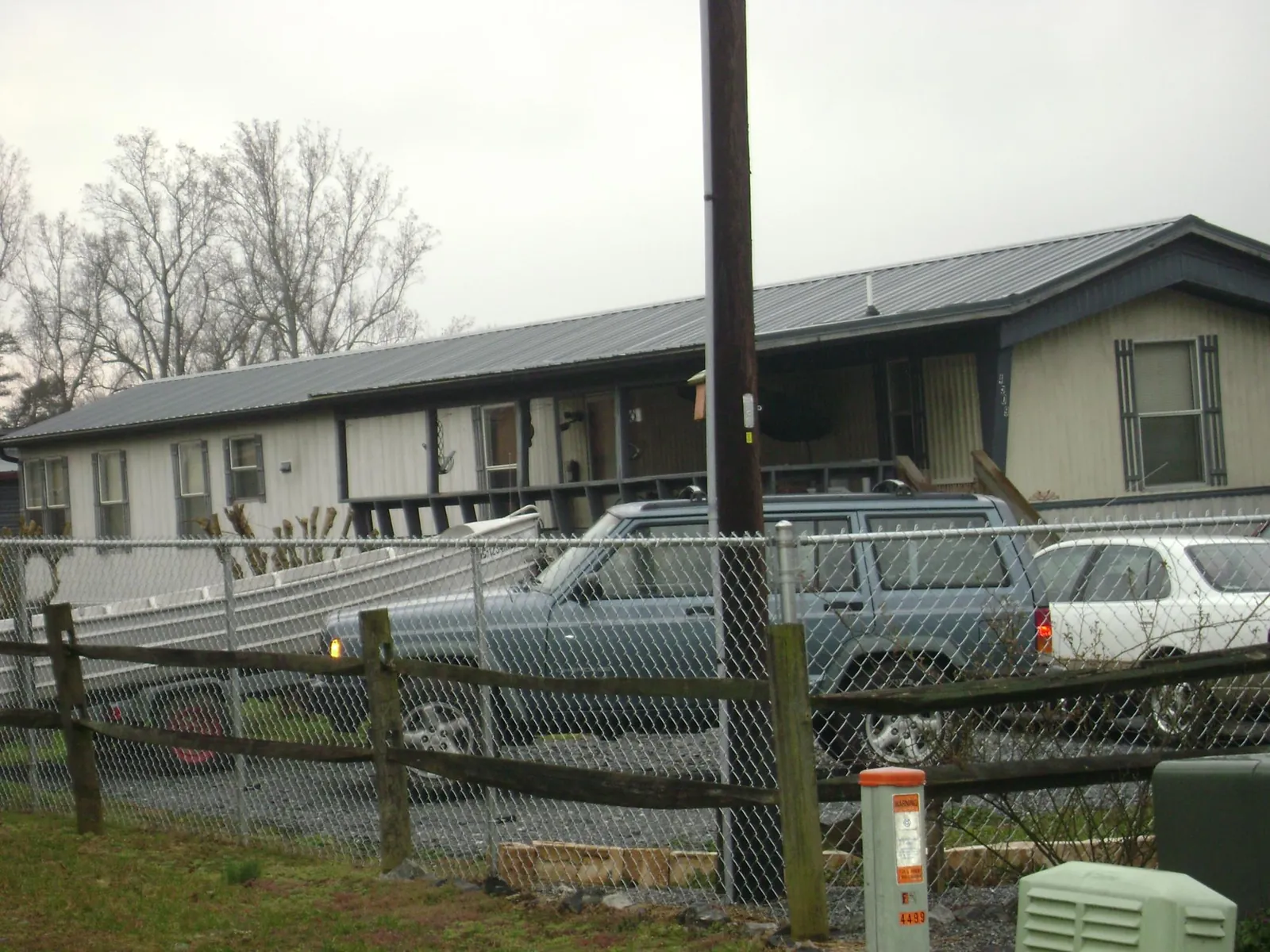 Dark metal roof on a long single story building behind a chain link fence in Conway