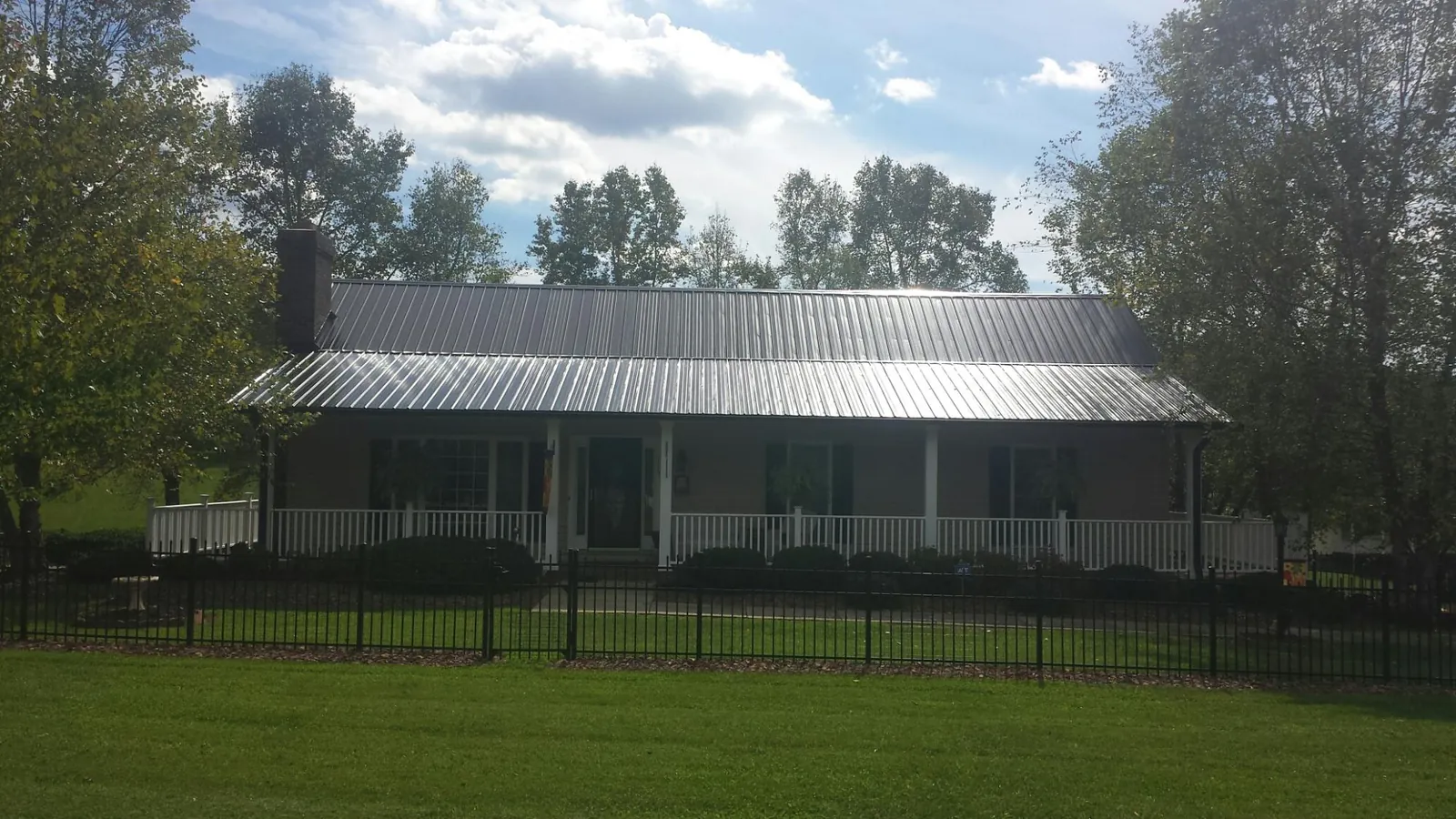 Gray metal roof on a brick ranch with a full width front porch — Gutter Guard Installation work by our crew in Conway