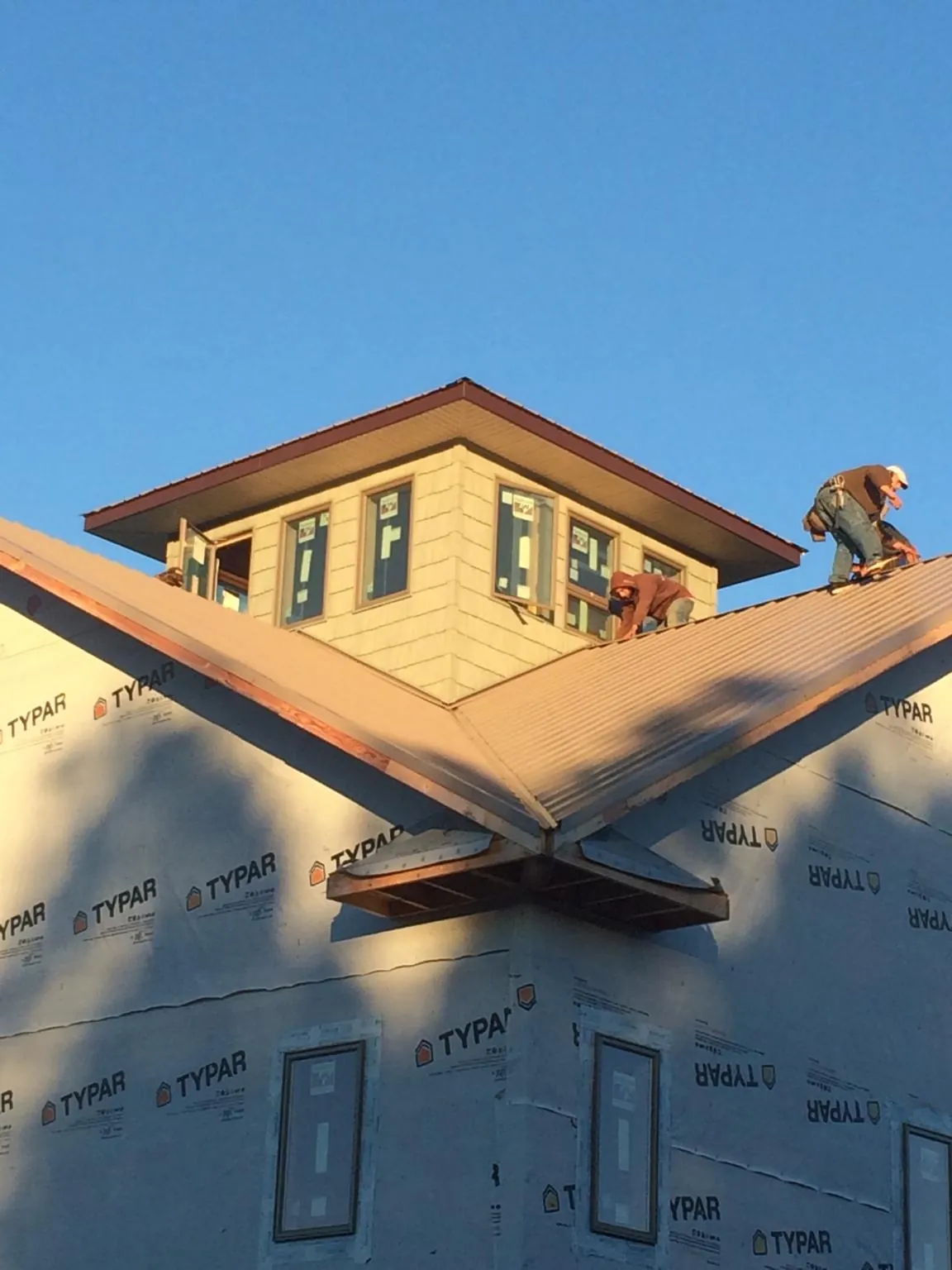 Roofers working around a rooftop cupola on a new metal roof at sunset — Roof Waterproofing in Conway by Roofing Brothers